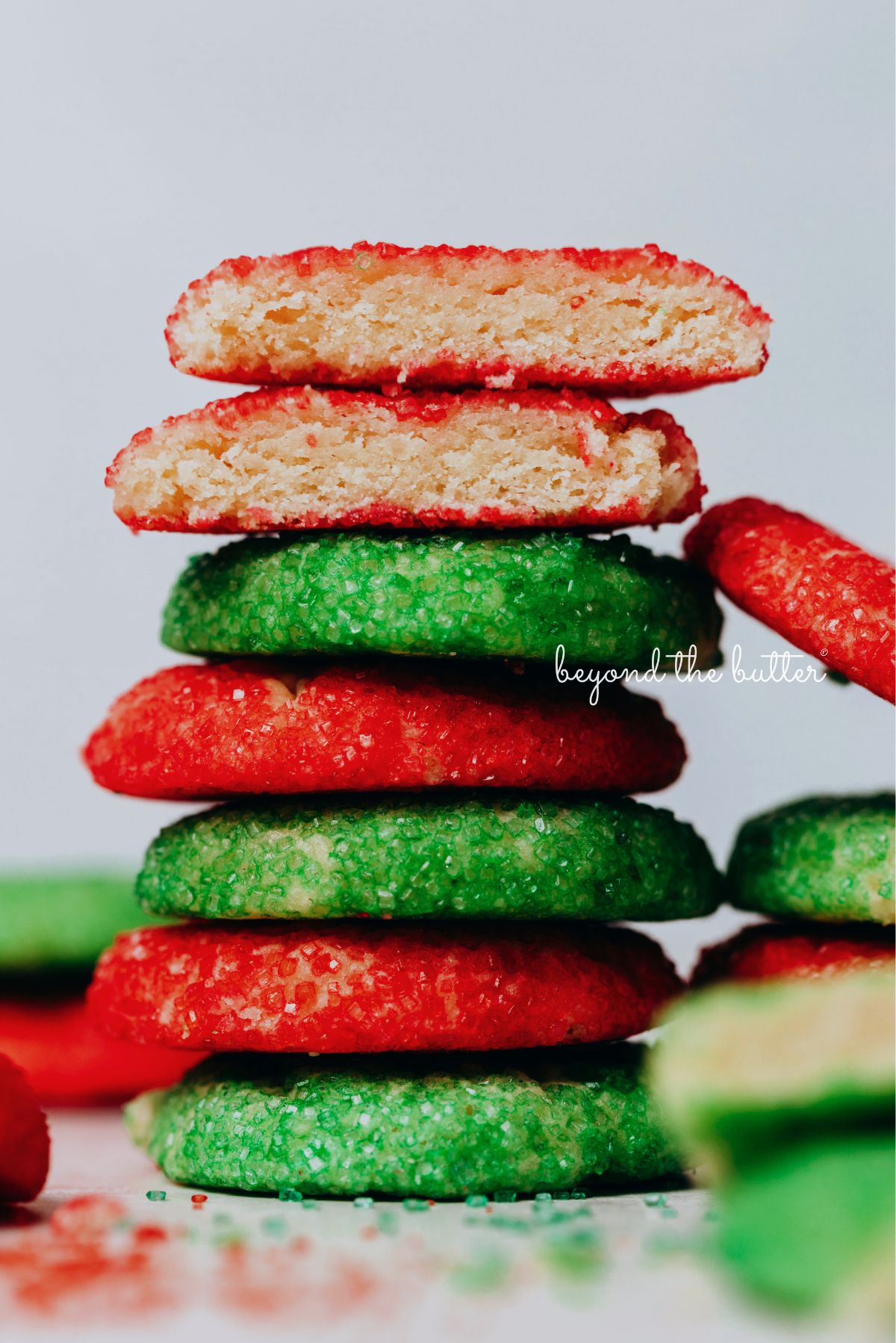 Stack of red and green sugared almond sprinkle cookies on a white background.
