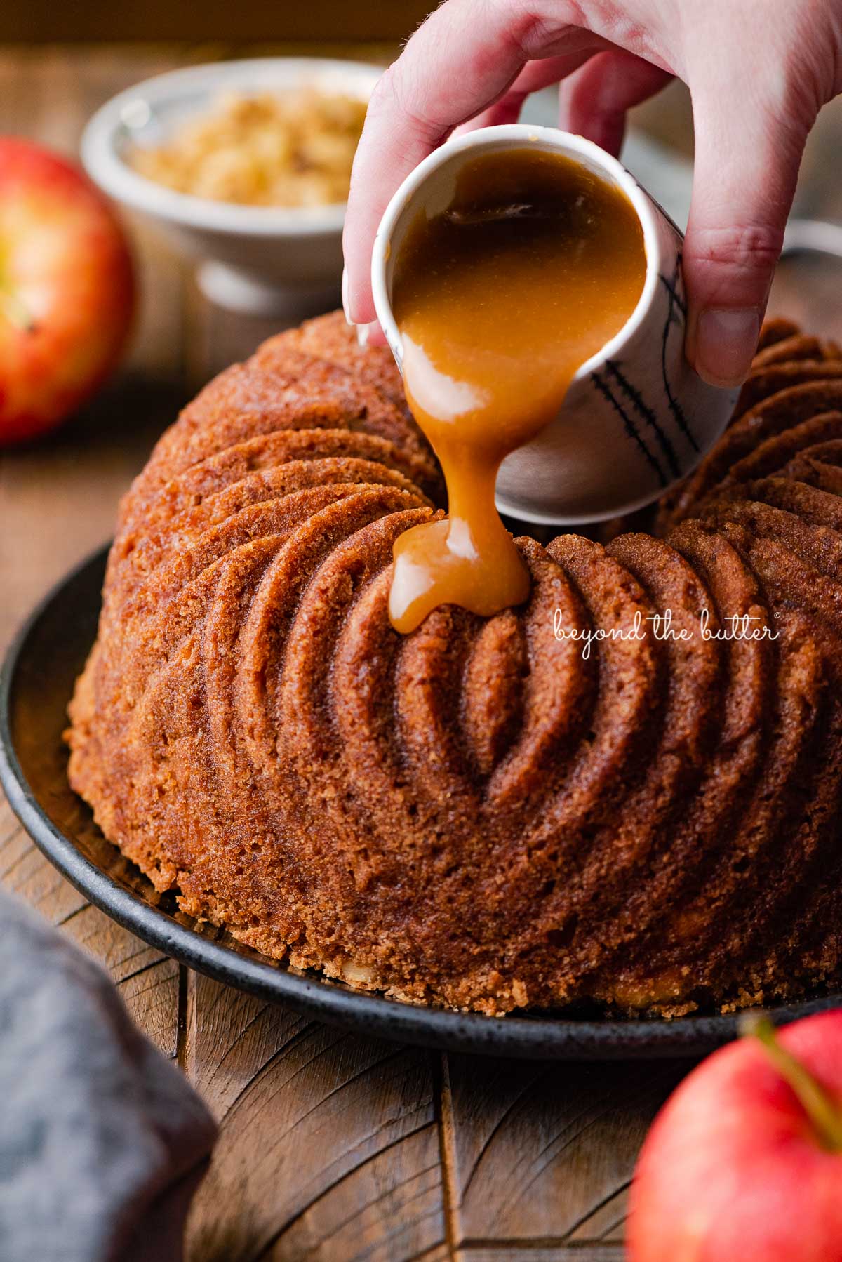 Pouring brown sugar glaze over top of warm apple bundt cake | © Luyiz®