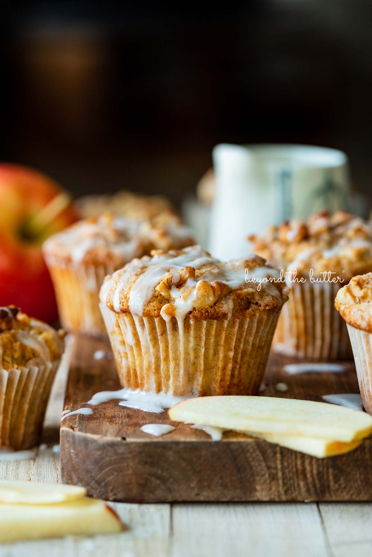 Warm apple cinnamon streusel muffins on a wood cutting board with slices of apples and vanilla glaze | © Luyiz®