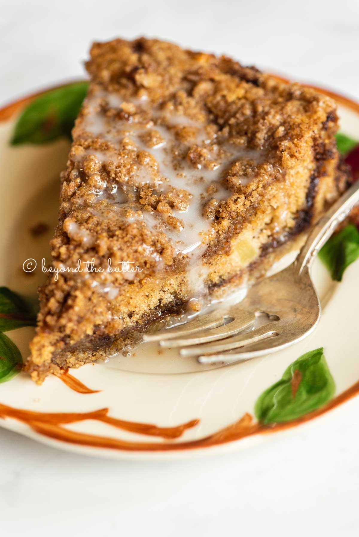 Slice of apple coffee cake on a dessert plate close up | All Images © Luyiz™