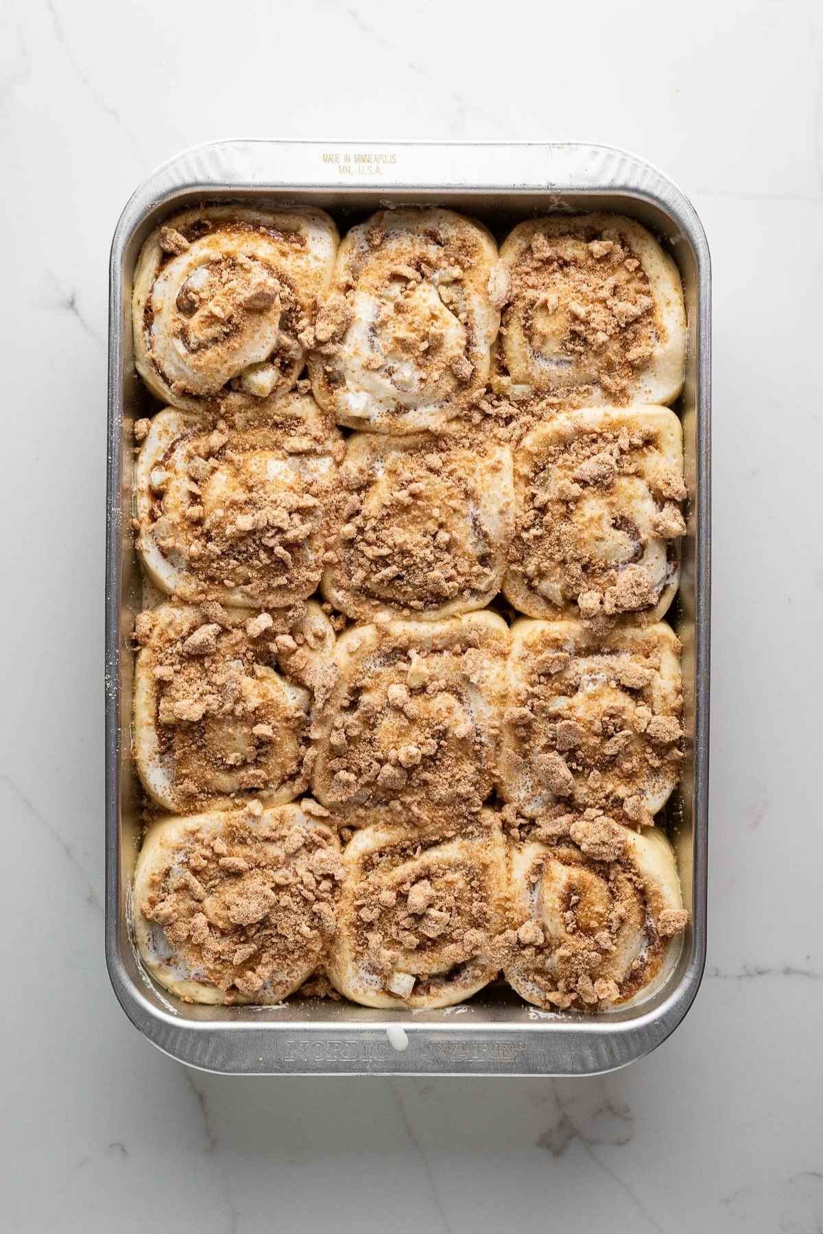 Apple cinnamon rolls topped with heavy cream and cinnamon streusel.