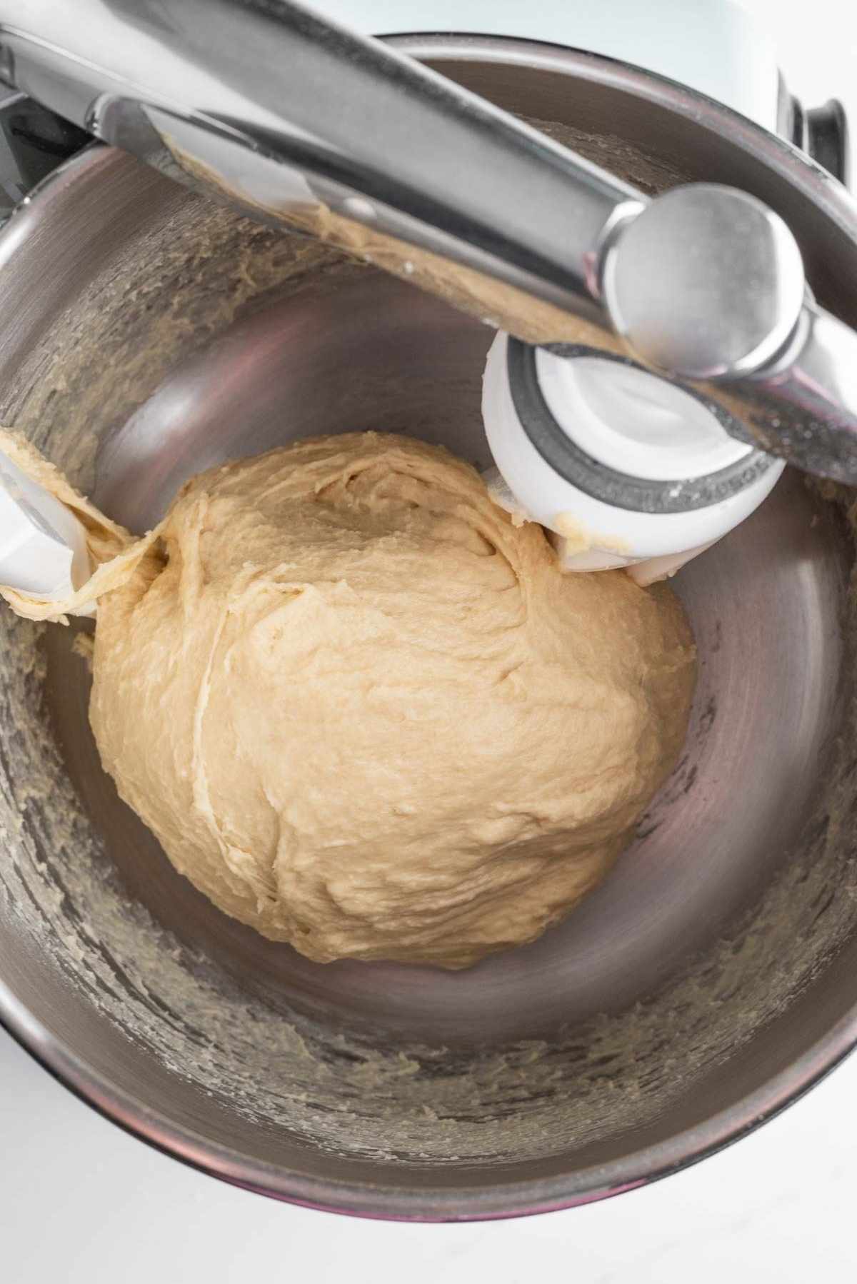 Kneaded cinnamon roll dough in the mixing bowl of an Ankarsrum mixer.