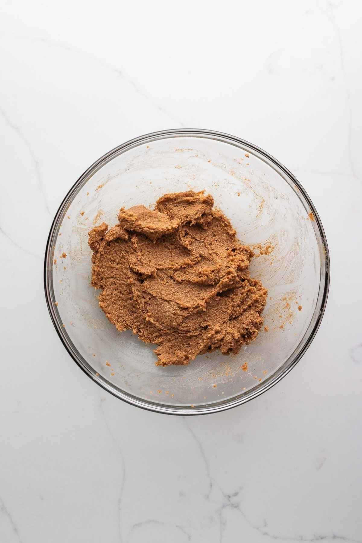 Brown sugar cinnamon filling in a small glass mixing bowl on a light grey marbled background.