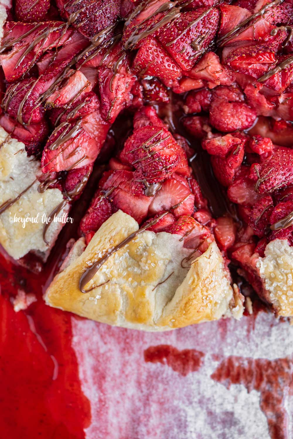Overhead image of a slice of Berry Nutella Galette on a baking sheet with Nutella drizzled over the top | All Images © Luyiz™