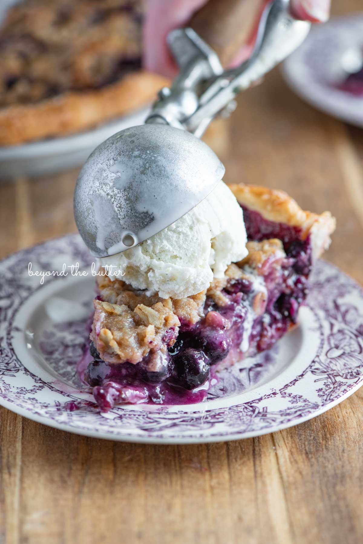 Slice of blueberry crumble pie with scoop of vanilla bean ice cream on top | © Luyiz®