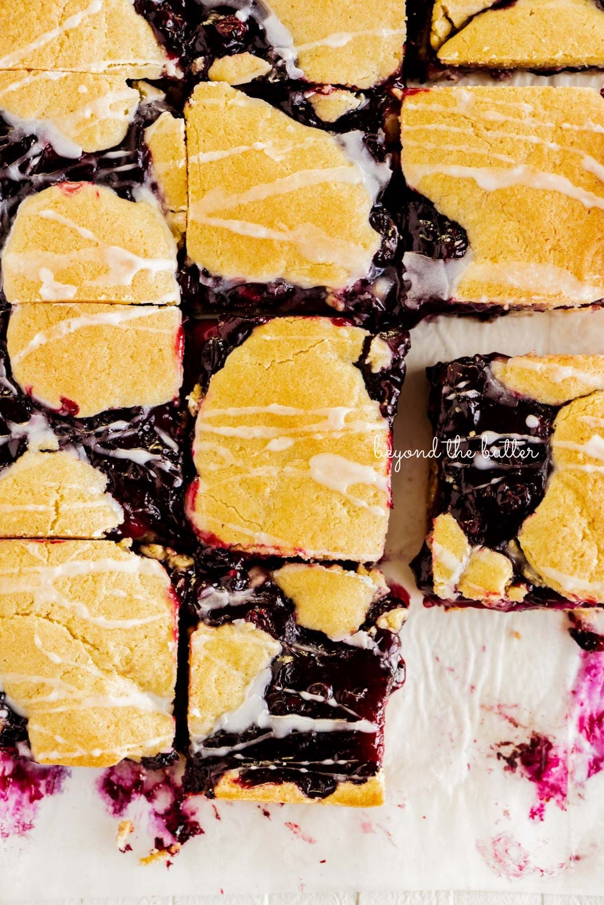 Slices of blueberry swirl coffee cake squares on a white parchment paper background.