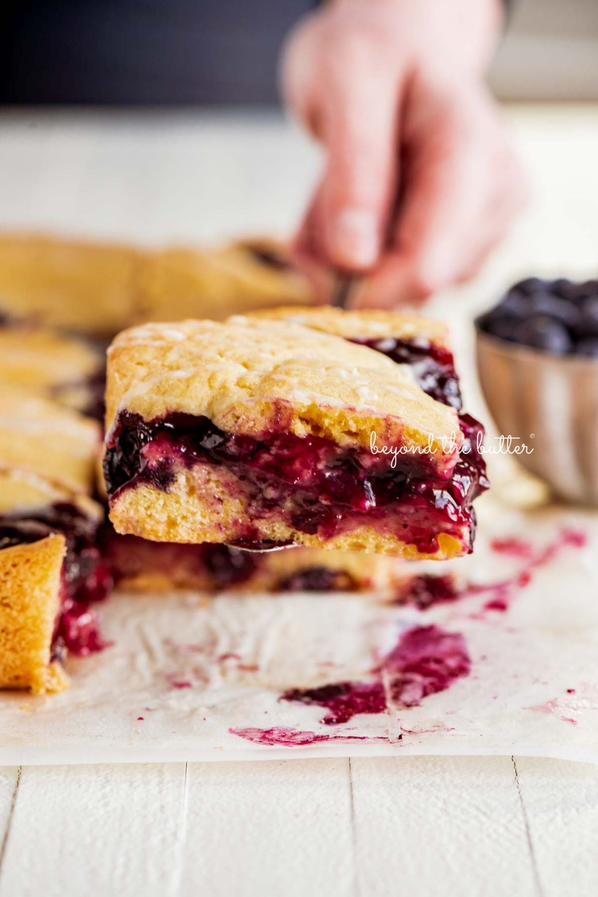 Serving a slice of freshly baked blueberry swirl coffee cake on wood table.