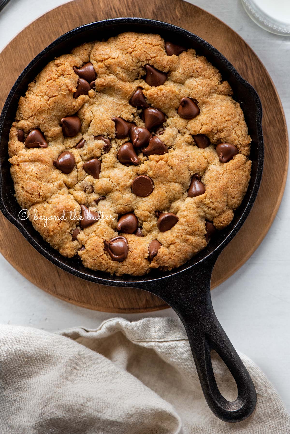 Just baked chocolate chip skillet cookies on light gray background with cloth napkin | All Images © Luyiz®