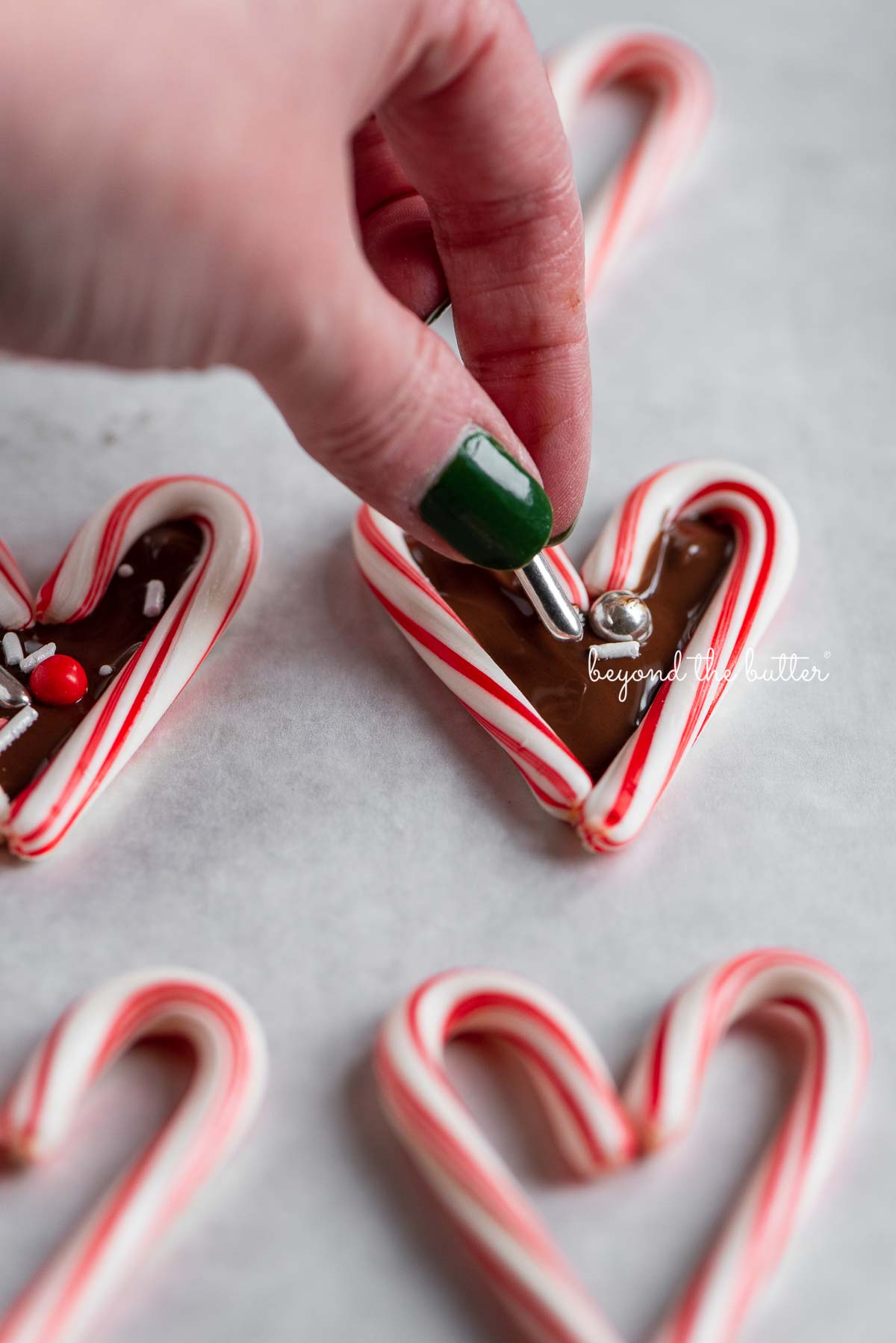 Adding holiday theme sprinkles to candy cane hearts filled with melted chocolate | © Luyiz®