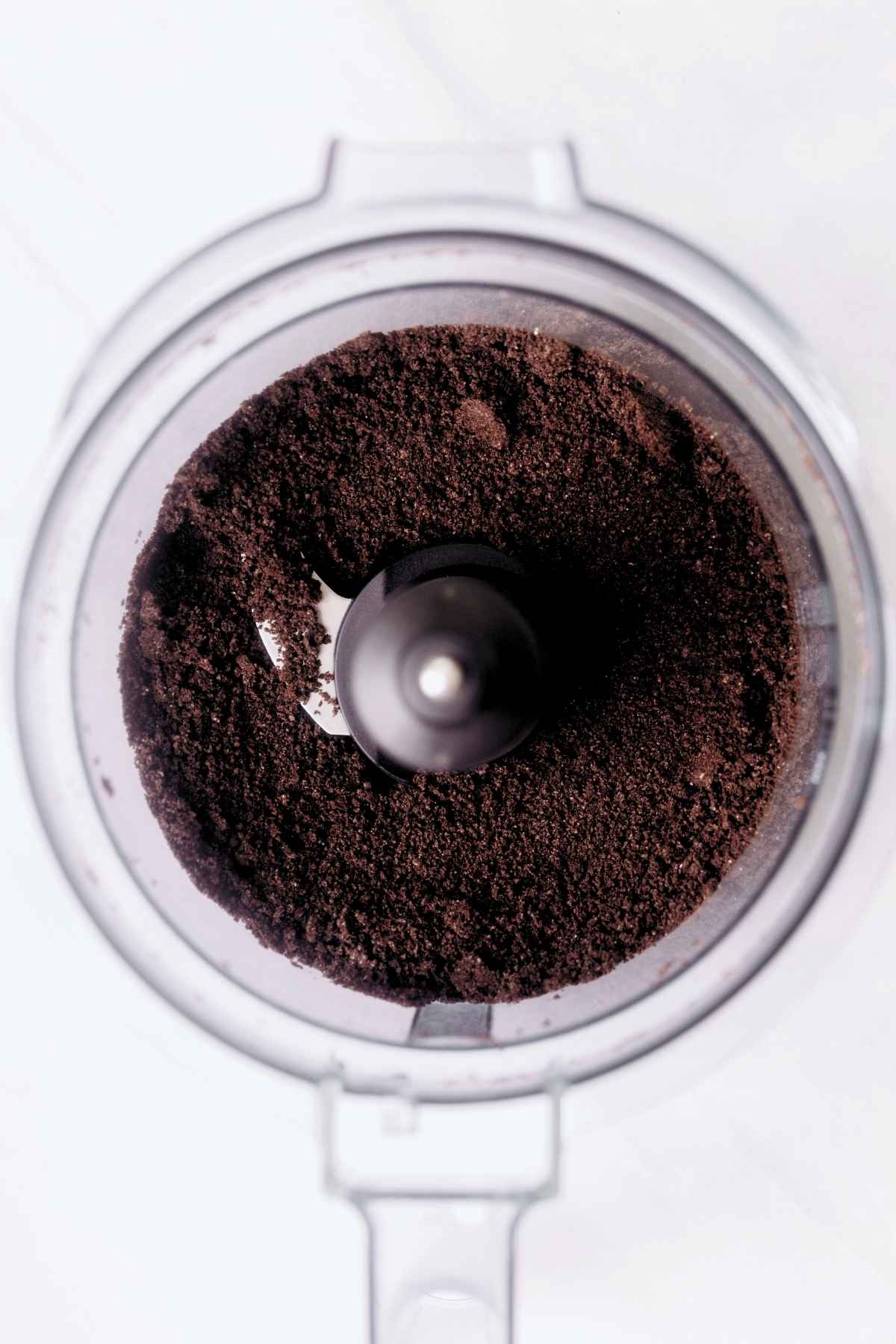 Chocolate sandwich cookie crumbs in a food processor with the lid off.