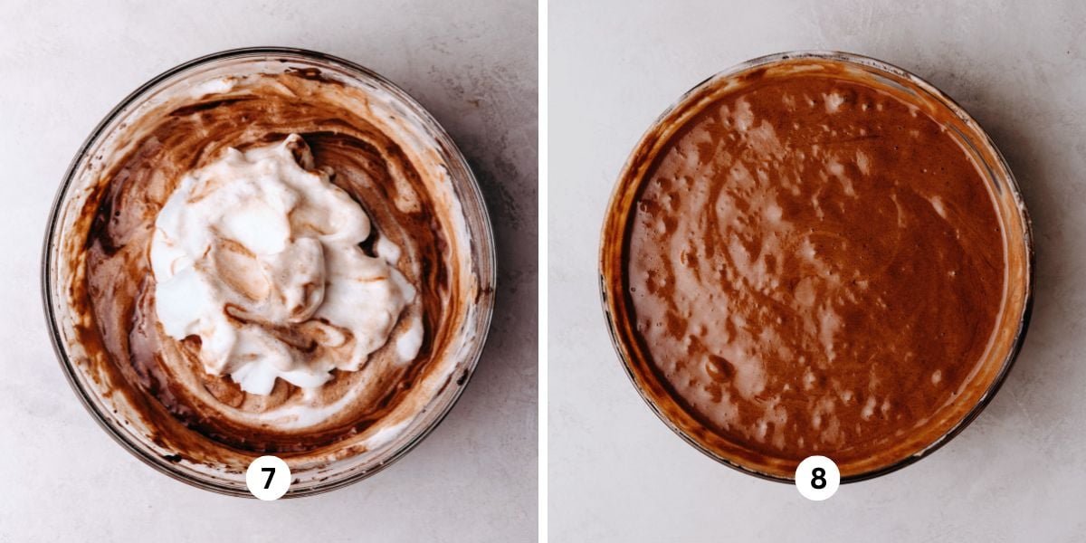 Folding meringue into chocolate chiffon cake batter in a large glass bowl on a white marbled background.
