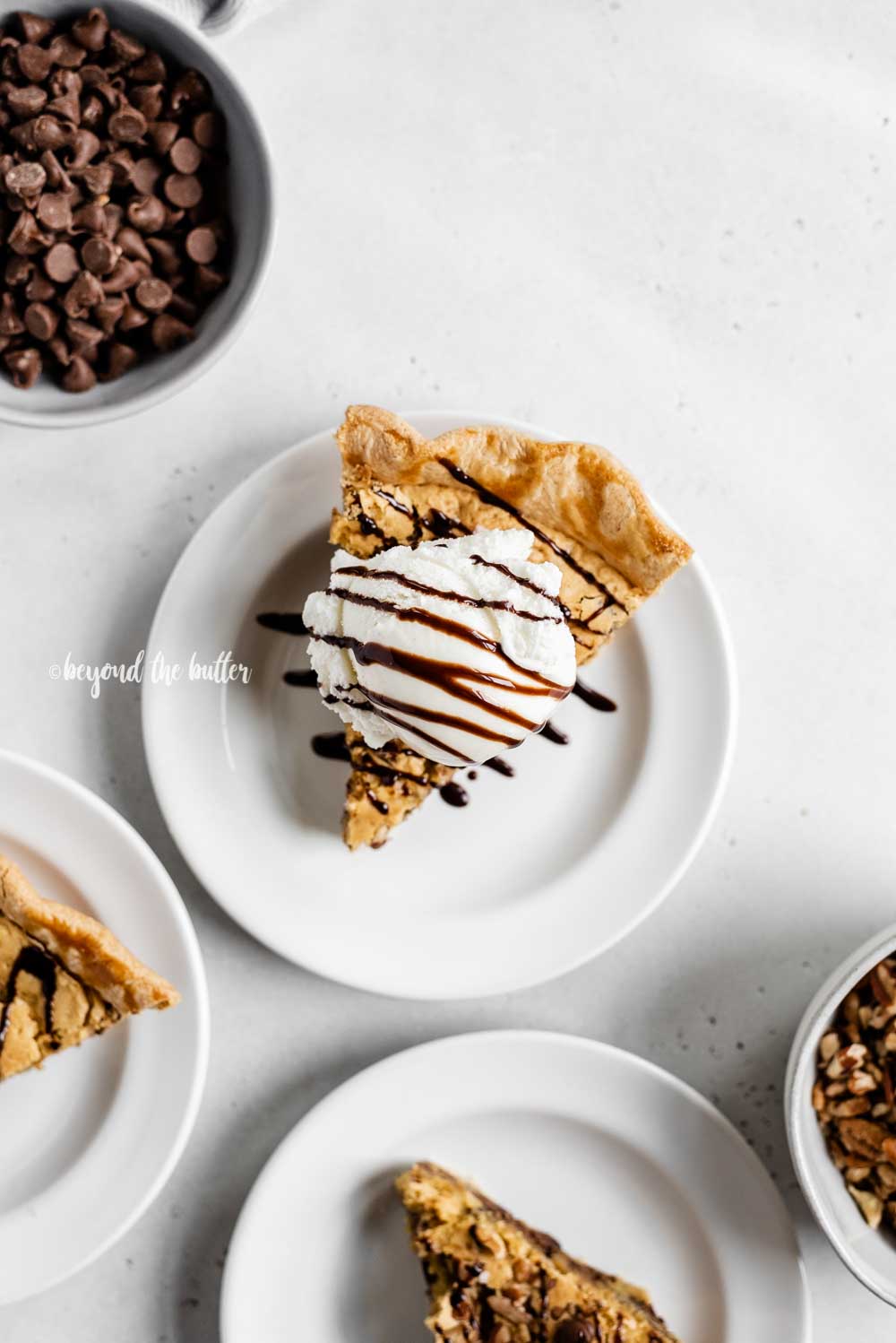 Overhead image of 3 slices of chocolate chip pie on dessert plates with one having a scoop of vanilla ice cream on top | All Images © Luyiz™