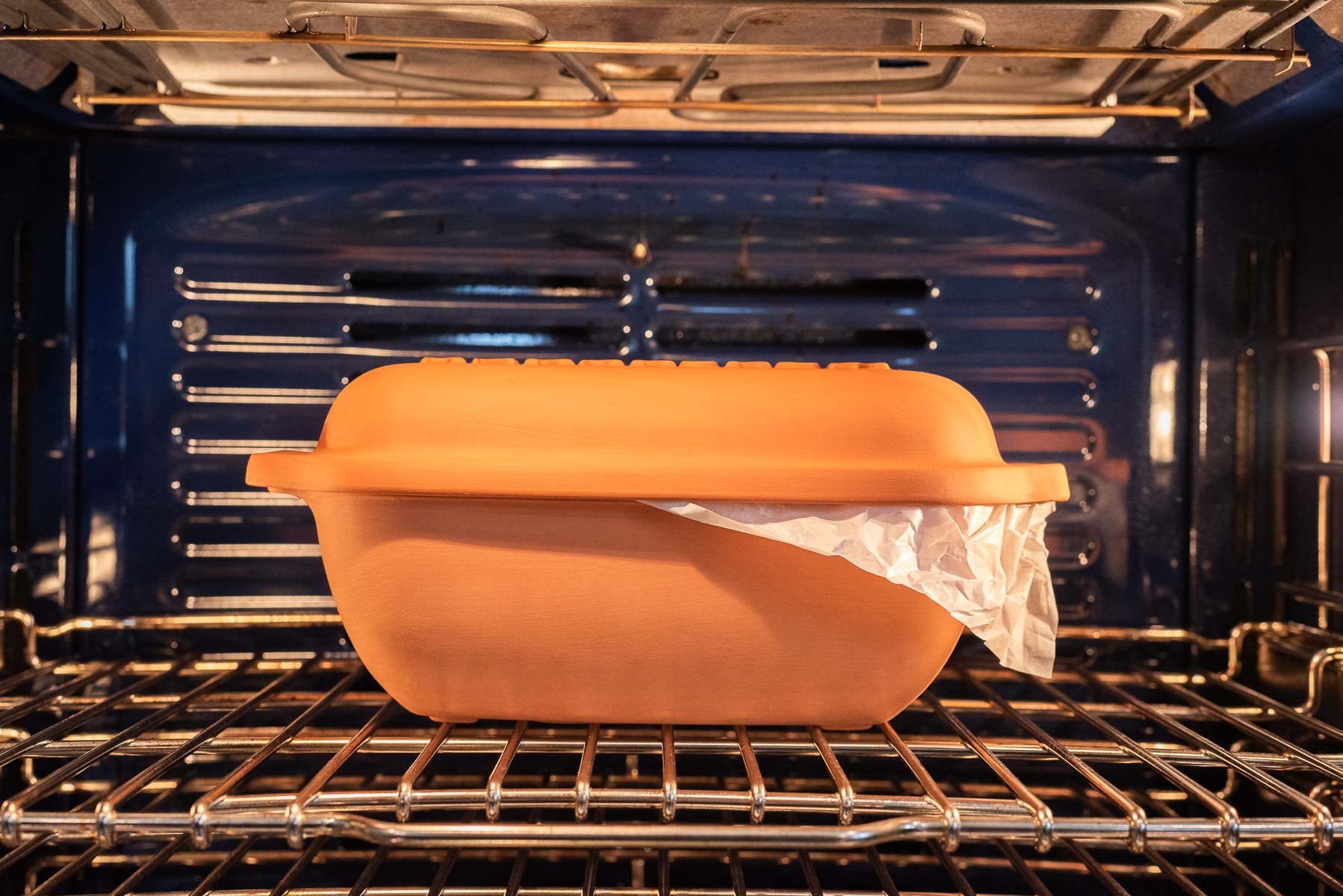 Chocolate croissant loaf in clay baker placed inside cold oven.