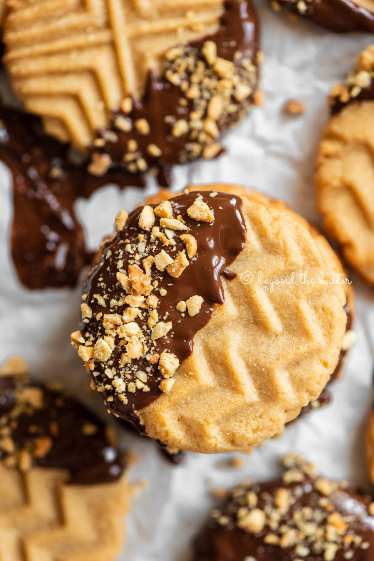 Baking sheet with randomly placed and stacked chocolate dipped peanut butter cookies | All Images © Luyiz®