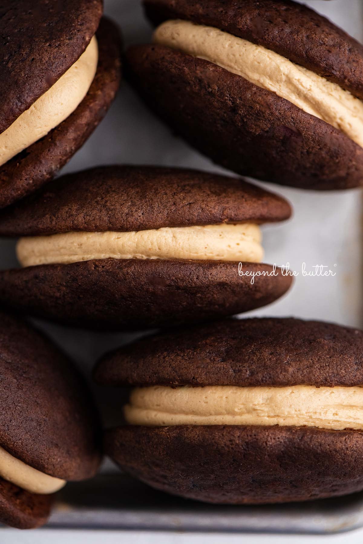 Chocolate peanut butter whoopie pies on a parchment lined baking pan | © Luyiz®