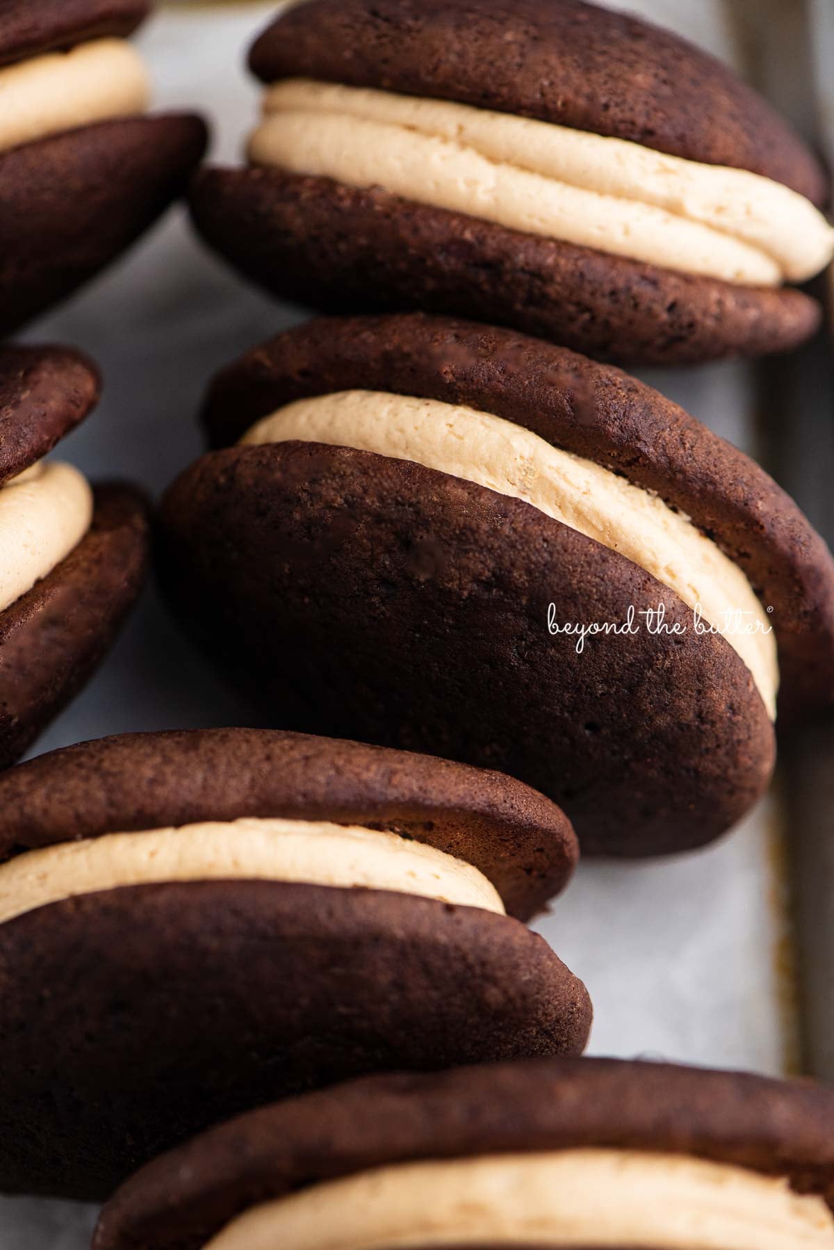 Chocolate peanut butter whoopie pies on a parchment lined baking pan | © Luyiz®
