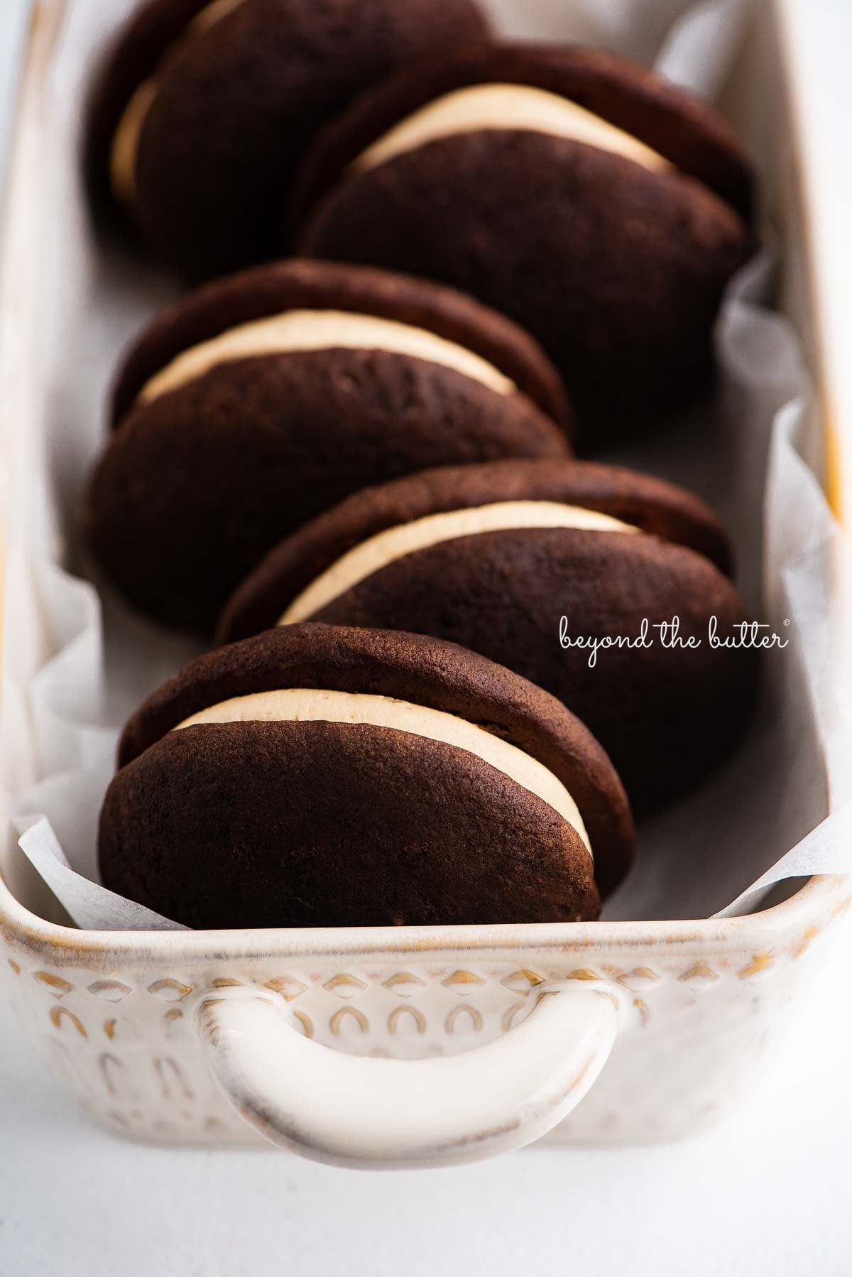 Ceramic loaf dish lined with parchment paper and chocolate peanut butter whoopie pies | © Luyiz®