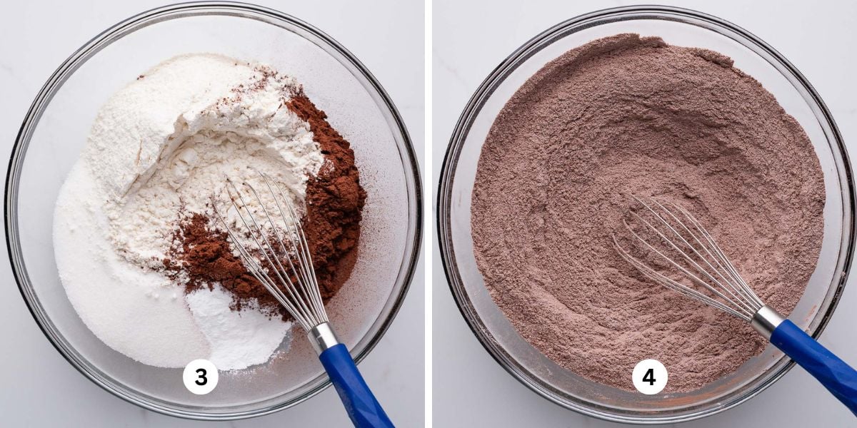 Small blue handle whisk resting in large glass bowl containing whisked flour, cocoa powder, sugar, baking powder, and salt on white marbled background.