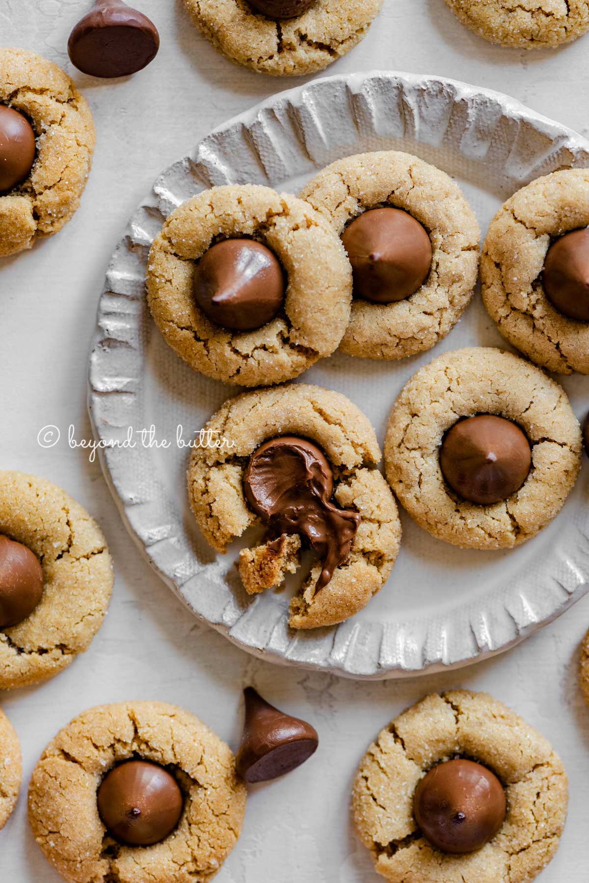 Small dessert plate full of classic peanut butter blossoms with one melted and split apart | All Images © Luyiz™