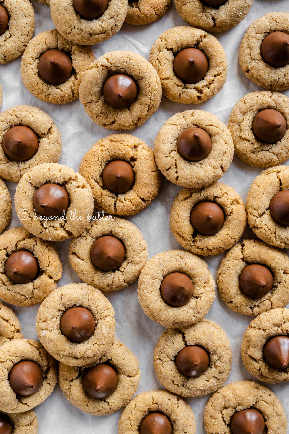 Classic peanut butter blossoms on a parchment paper lined baking sheet | Luyiz®