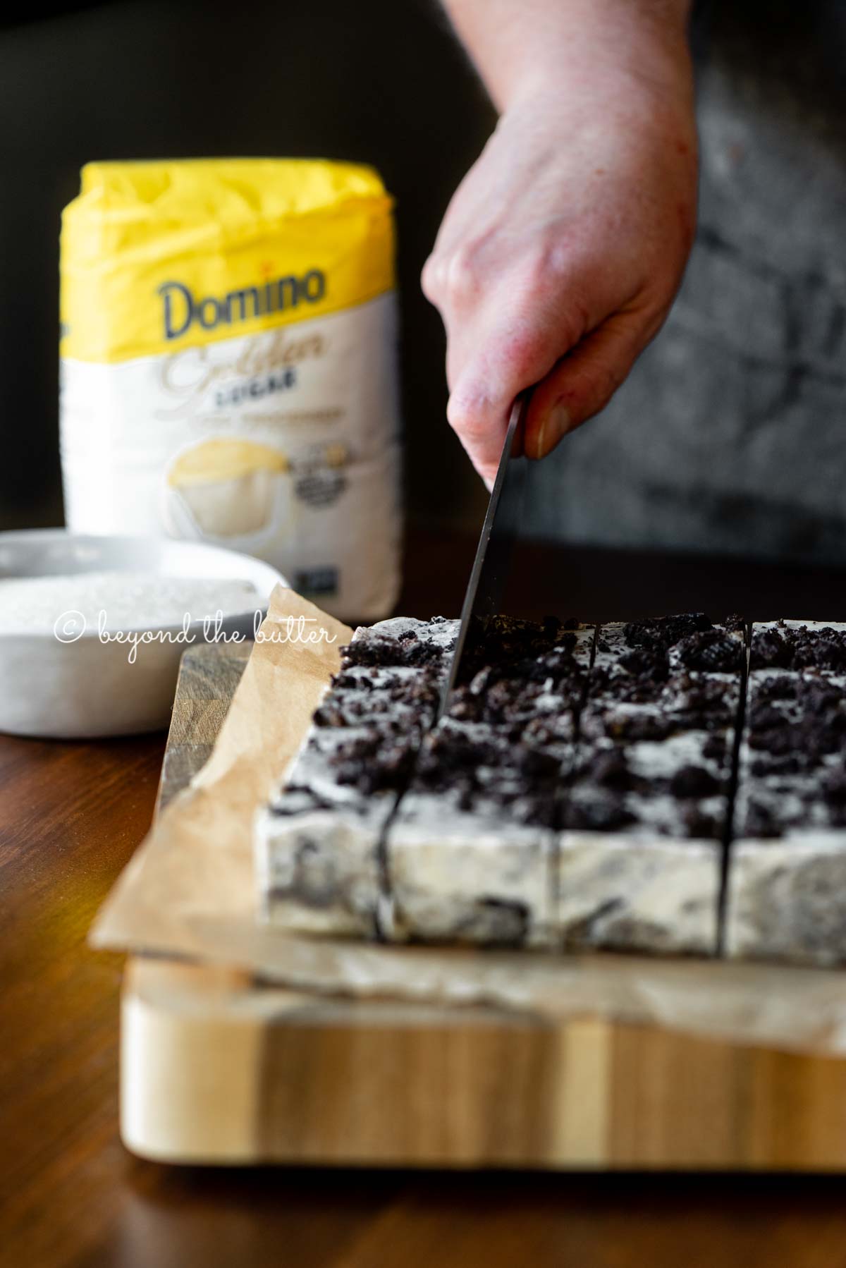 Cutting the cookies and cream fudge with small bag of Domino® Golden Sugar in the background | All Images © Luyiz®