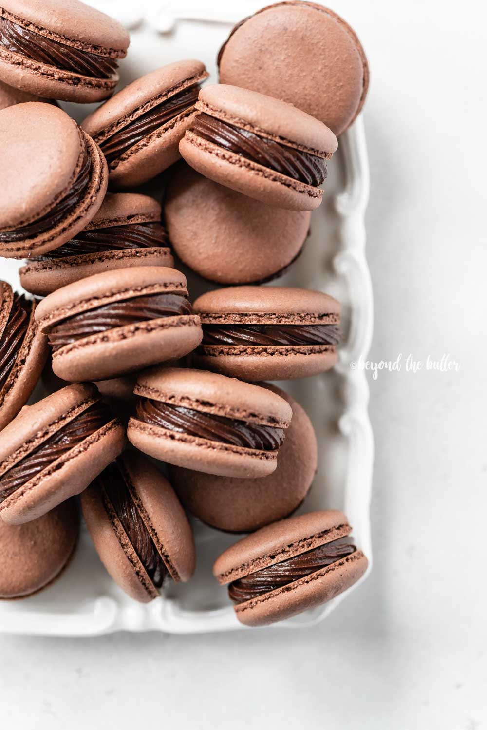 Overhead image of rectangular white plate full of chocolate macarons | All Images © Luyiz™