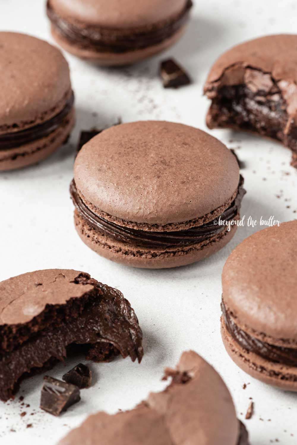 Scattered dark chocolate macarons with some broken or pulled apart | All Images © Luyiz™