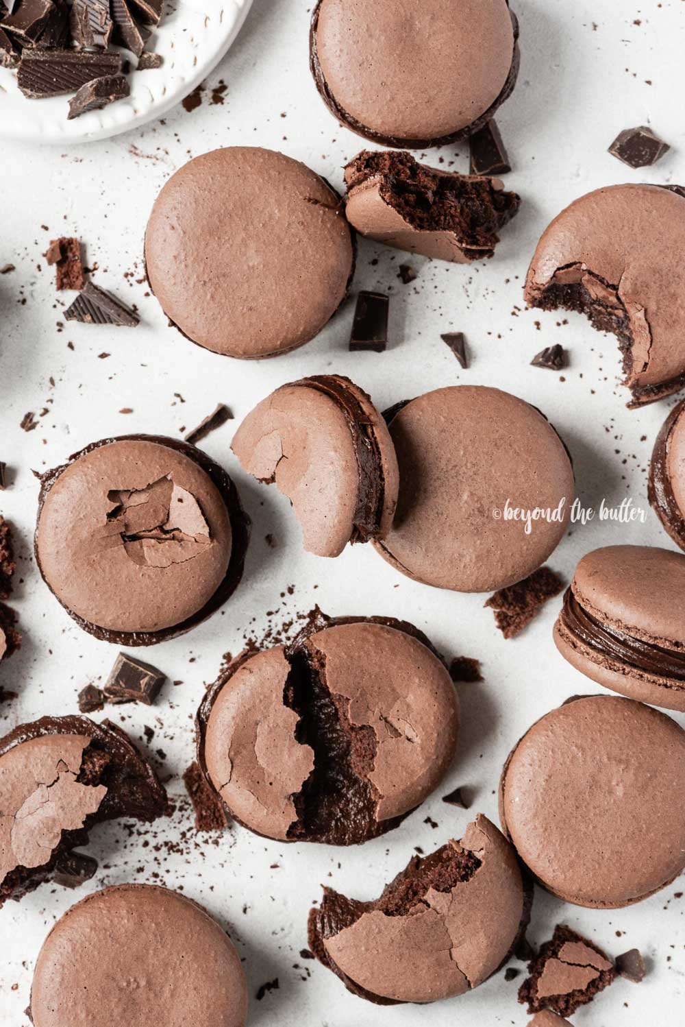 Scattered dark chocolate macarons with some broken or pulled apart | All Images © Luyiz™