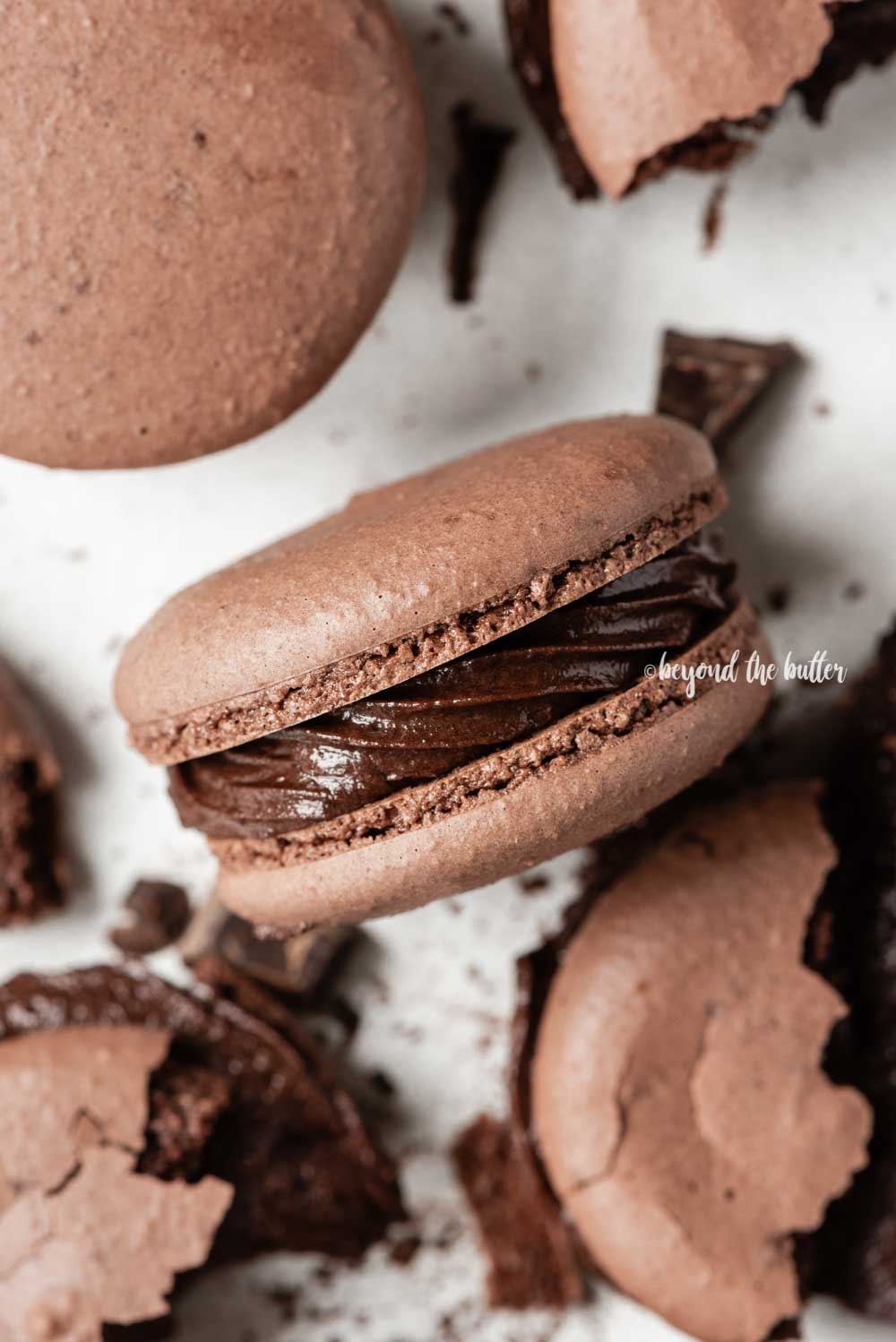 Overhead image of scattered dark chocolate macarons with close up and centered on its side | All Images © Luyiz™