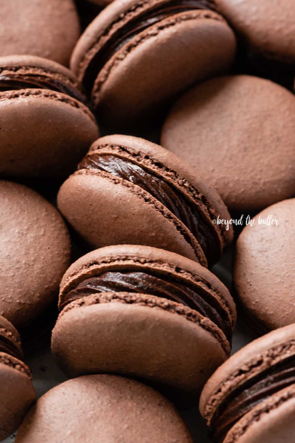 Angled image of randomly placed dark chocolate macarons | All Images © Luyiz™