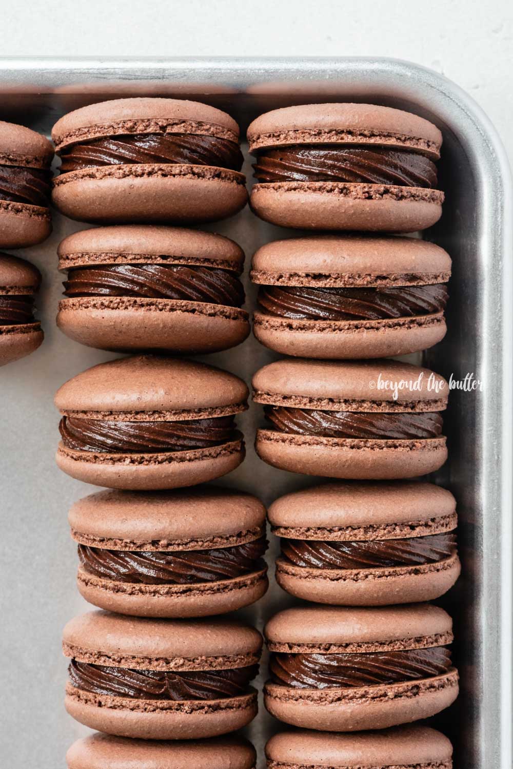 Small baking tray lined with dark chocolate macarons | All Images © Luyiz™