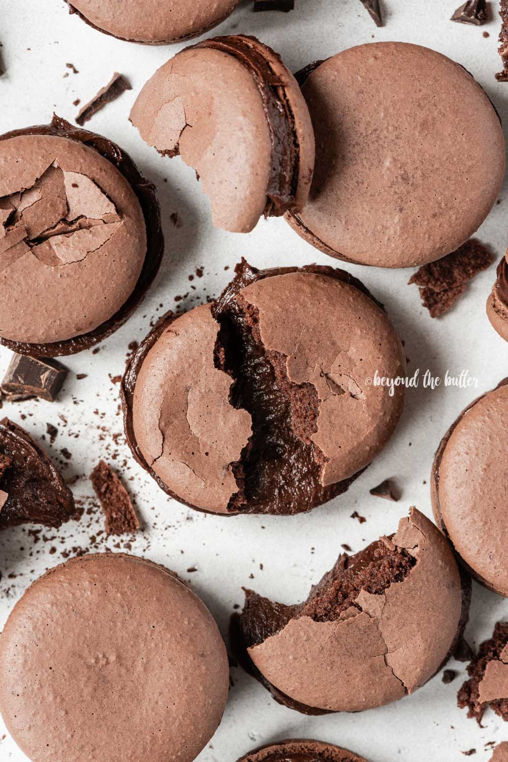 Scattered dark chocolate macarons with some broken or pulled apart | All Images © Luyiz™