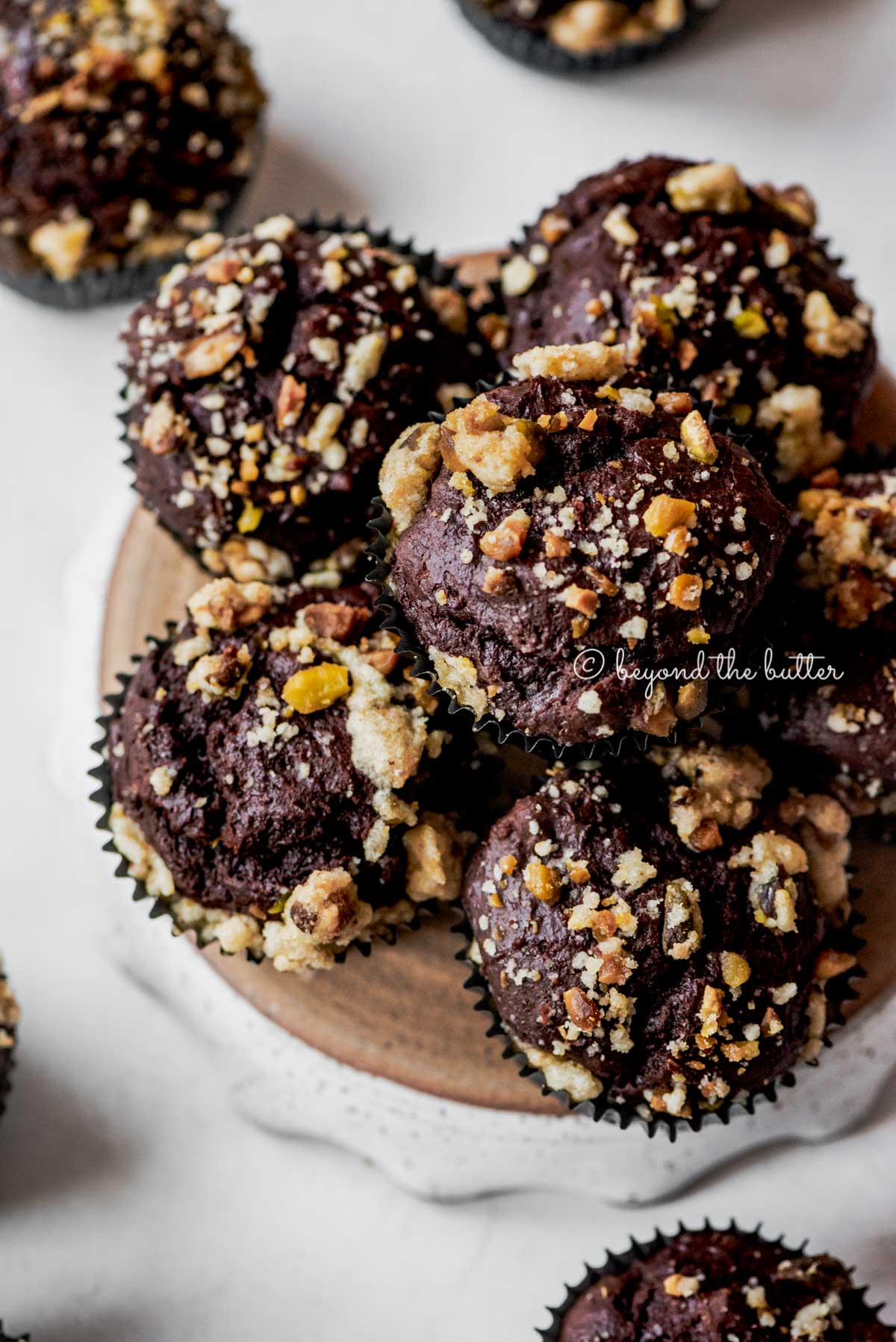 Small plate of dark chocolate pistachio cream cheese muffins on gray background | All Images © Luyiz®