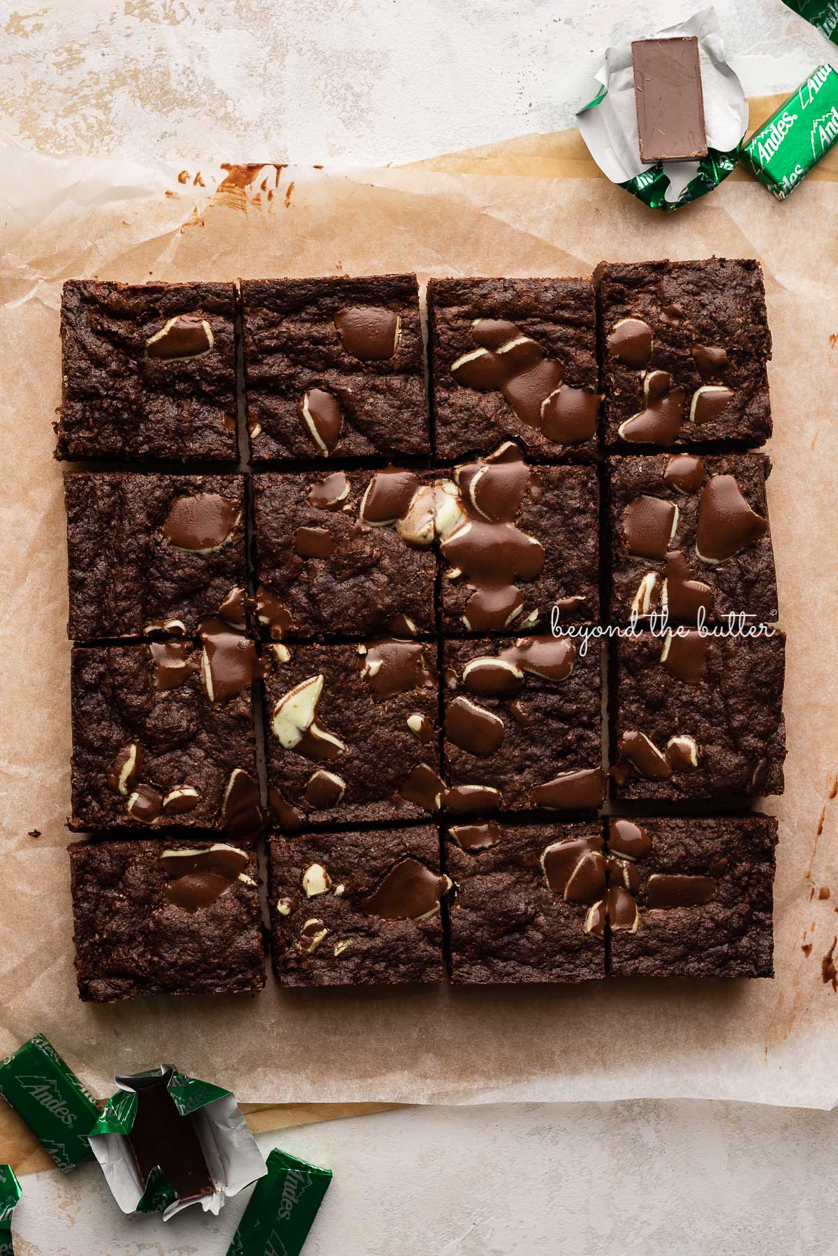 Just cut double chocolate mint brownies on brown and white sheets of crumbled parchment paper with andes mints around them | © Luyiz®