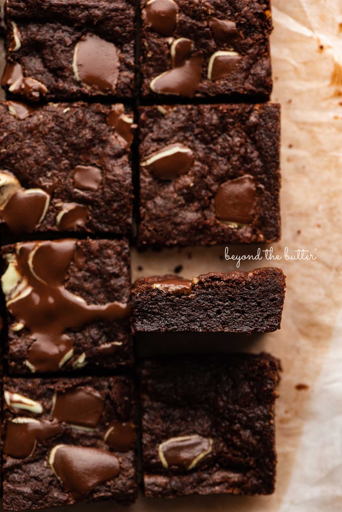 Double chocolate mint brownies on brown parchment paper background with the center brownie on its side | © Luyiz®
