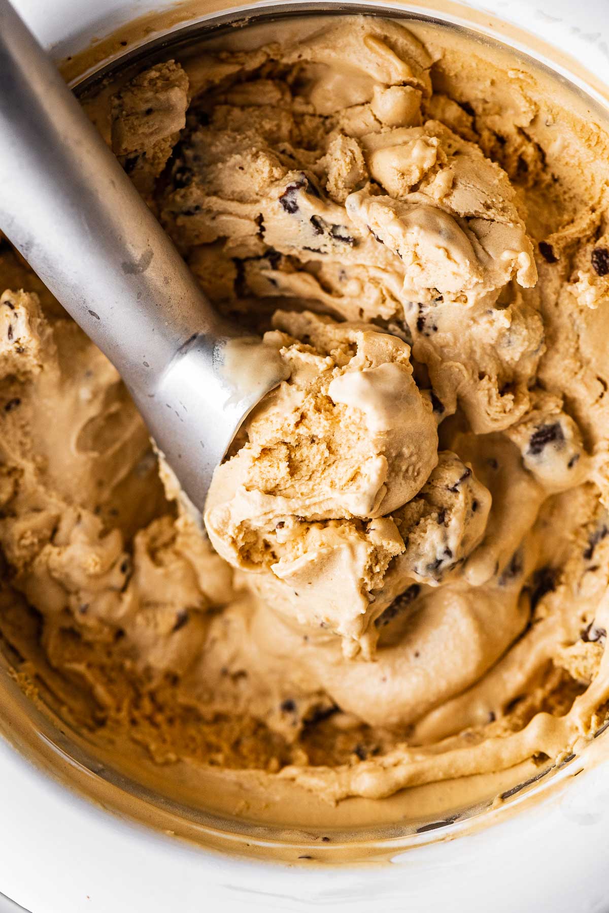 Ice cream sccop in a container of dulce de leche ice cream with chocolate covered pretzels | © Luyiz®
