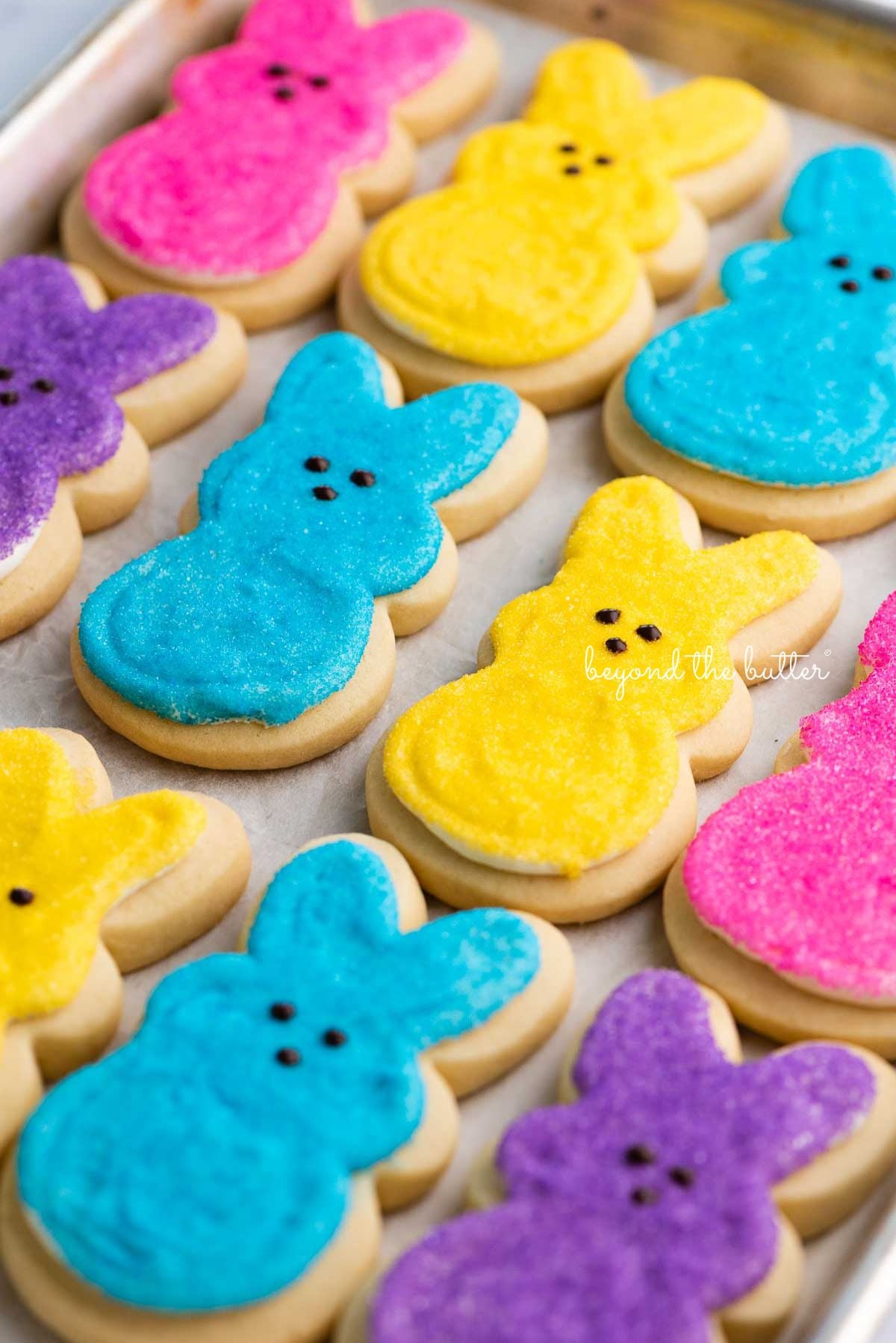 Easter bunny cut out sugar cookies on a parchment paper lined baking sheet.