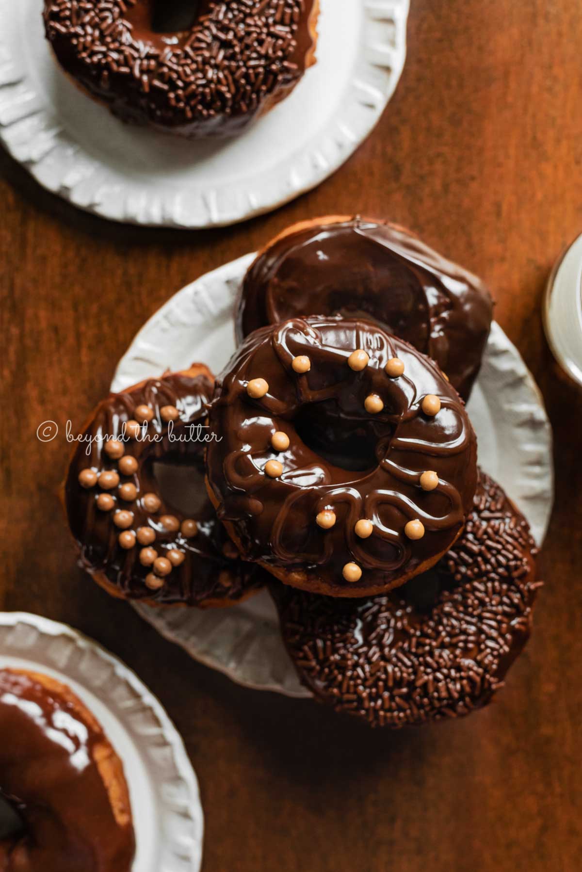 Easy homemade donuts from scratch topped with chocolate glaze stacked on a dessert plate | All Images © Luyiz™
