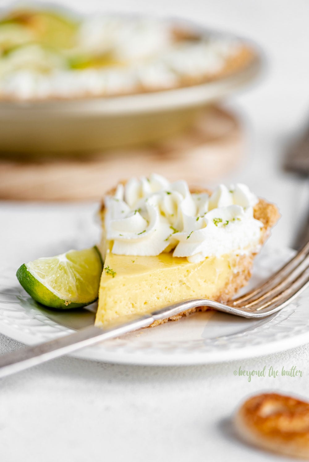 Easy Key Lime Pie decorated with homemade whipped cream, puff pastry twists, and sliced limes | Image and Copyright Policy: © Luyiz, LLC