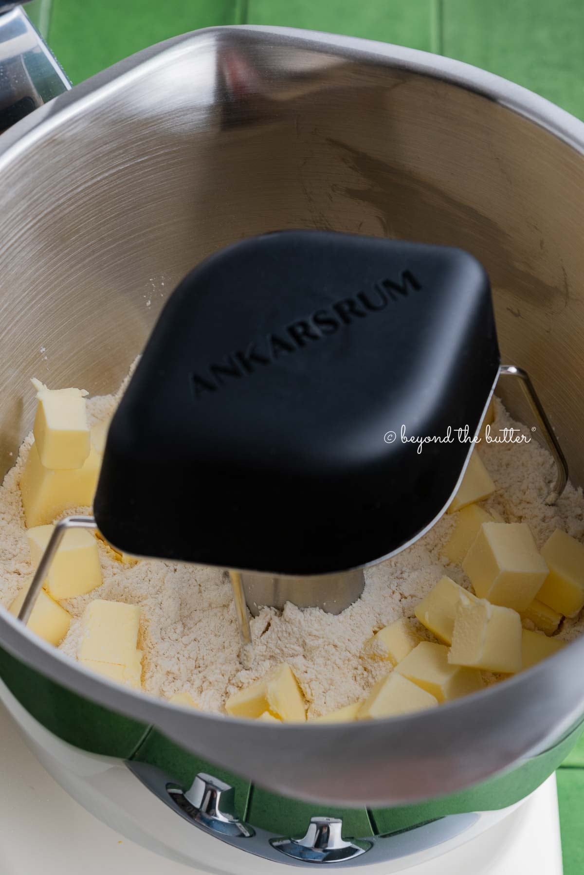 Ankarsrum stainless steel beater bowl with new premium beater set attachment mixing pie crust mixture and cold cubed butter together.