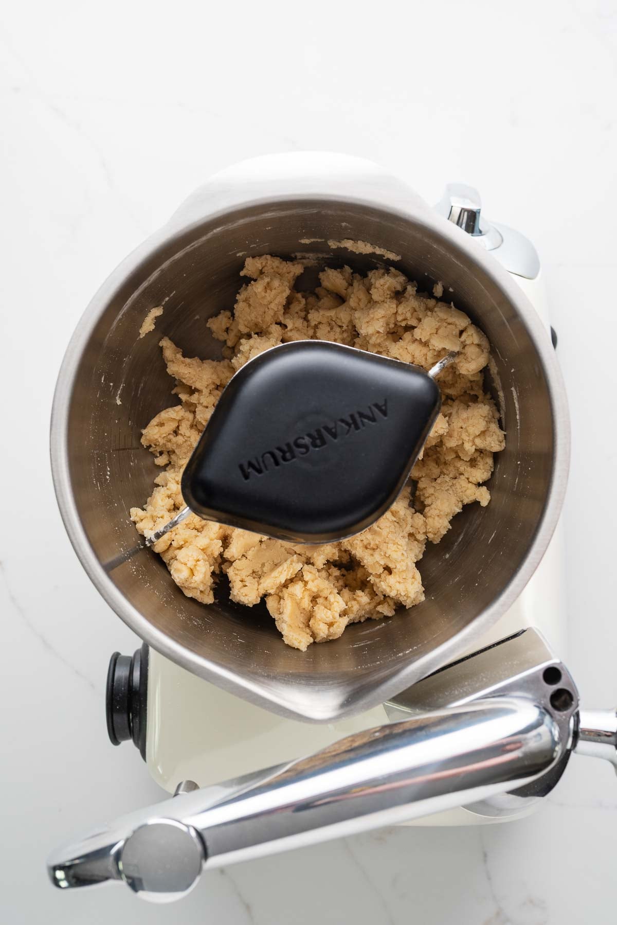 Flour, salt, sugar, cold cubed butter, and ice cold butter mixed together in a creme light colored ankarsrum assistent original mixer and stainless steel beater bowl with their new premium beater set.