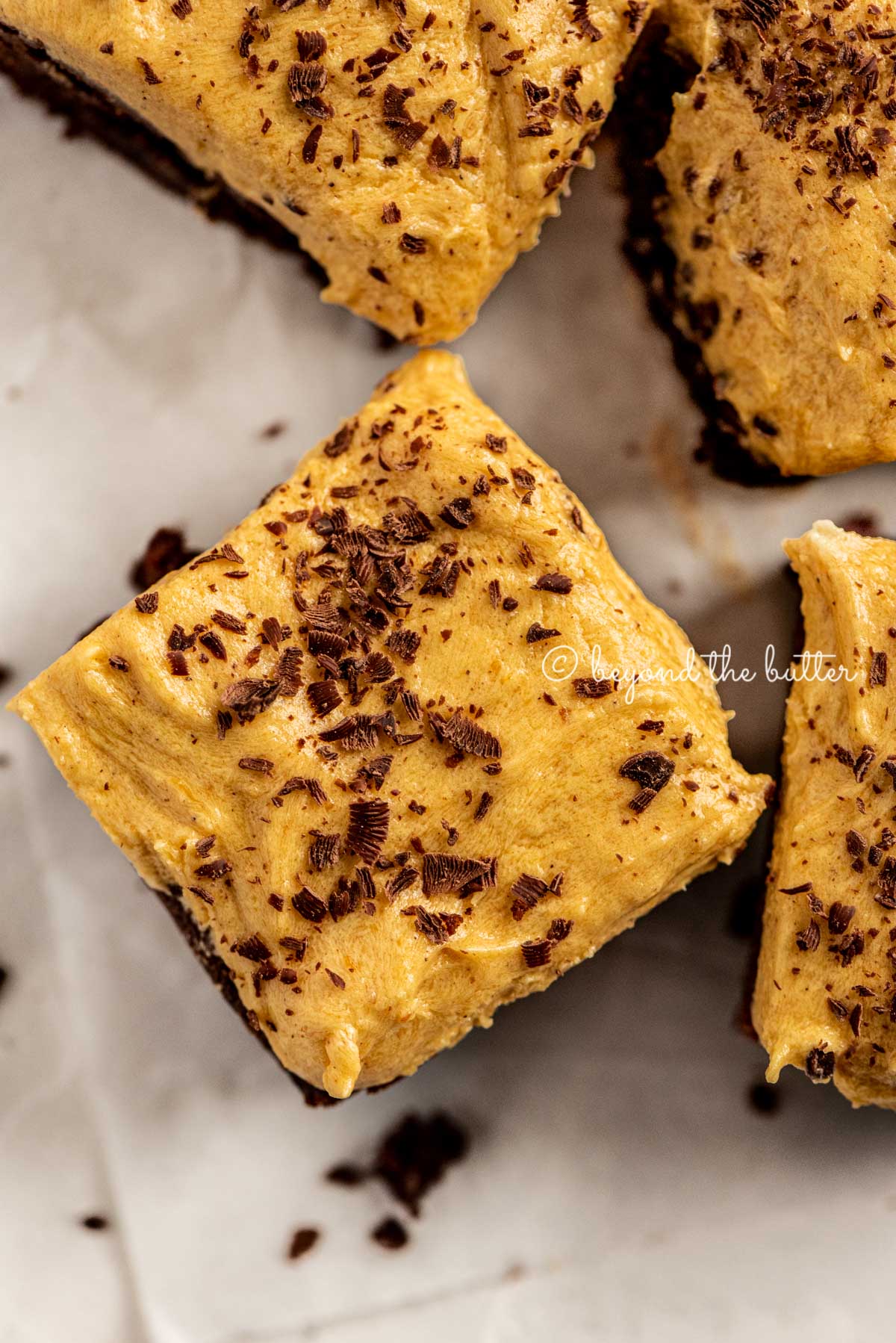 closeup of fudgy chocolate brownies frosted with pumpkin buttercream and topped with chocolate shavings | All Images © Luyiz™