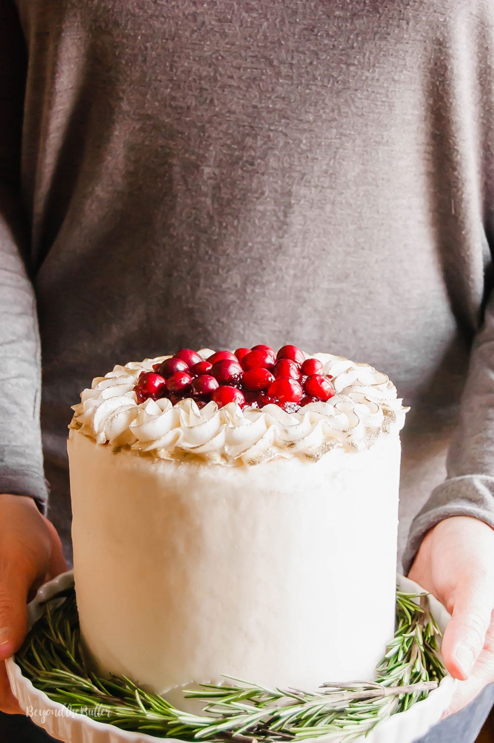Gingerbread Cake | Person holding Gingerbread Cake with Maple Buttercream Frosting and Cranberry Compote on a cake stand | Image Credit: Luyiz, LLC