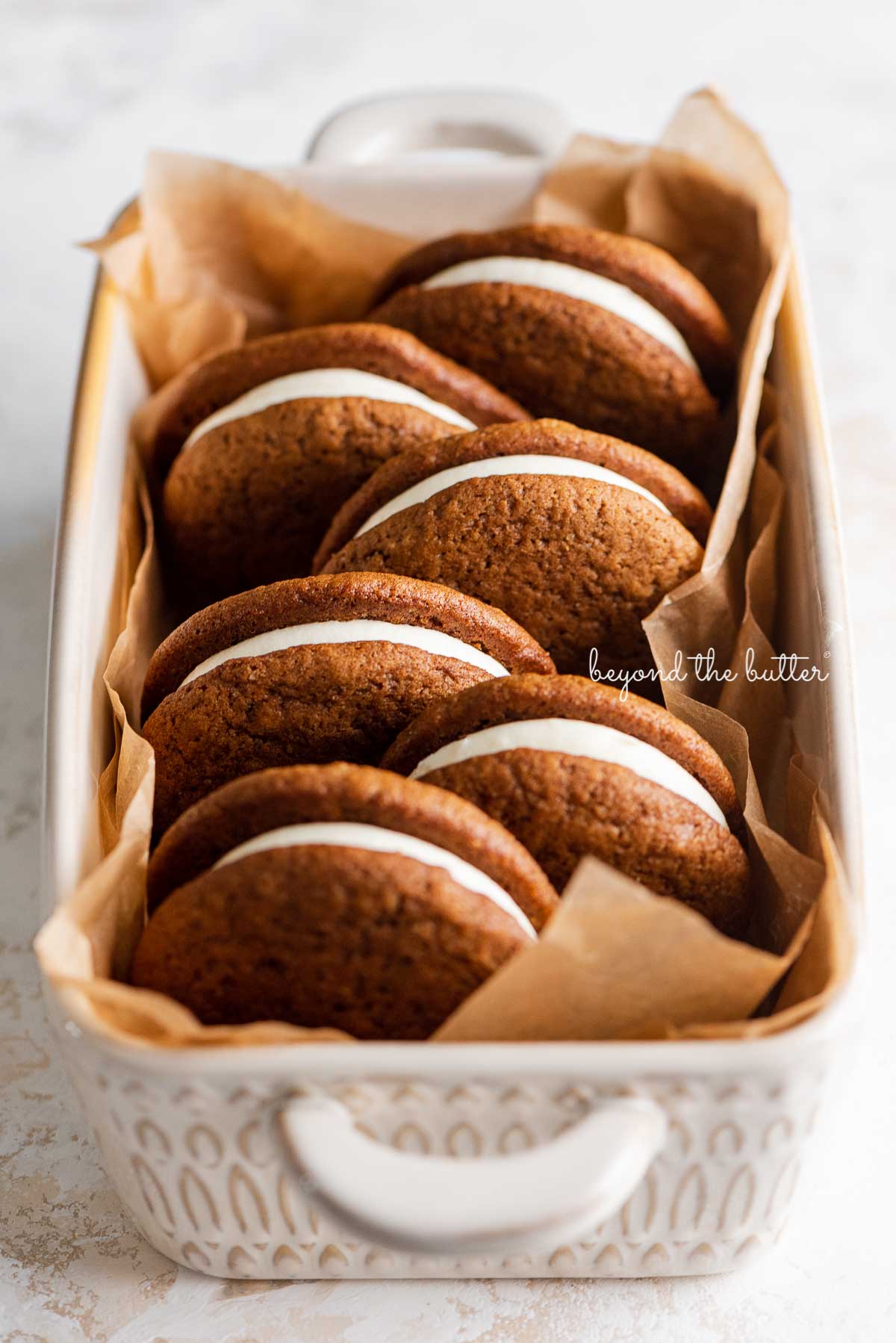Natural parchment paper lined ceramic baking pan with homemade gingerbread whoopie pies | © Luyiz®