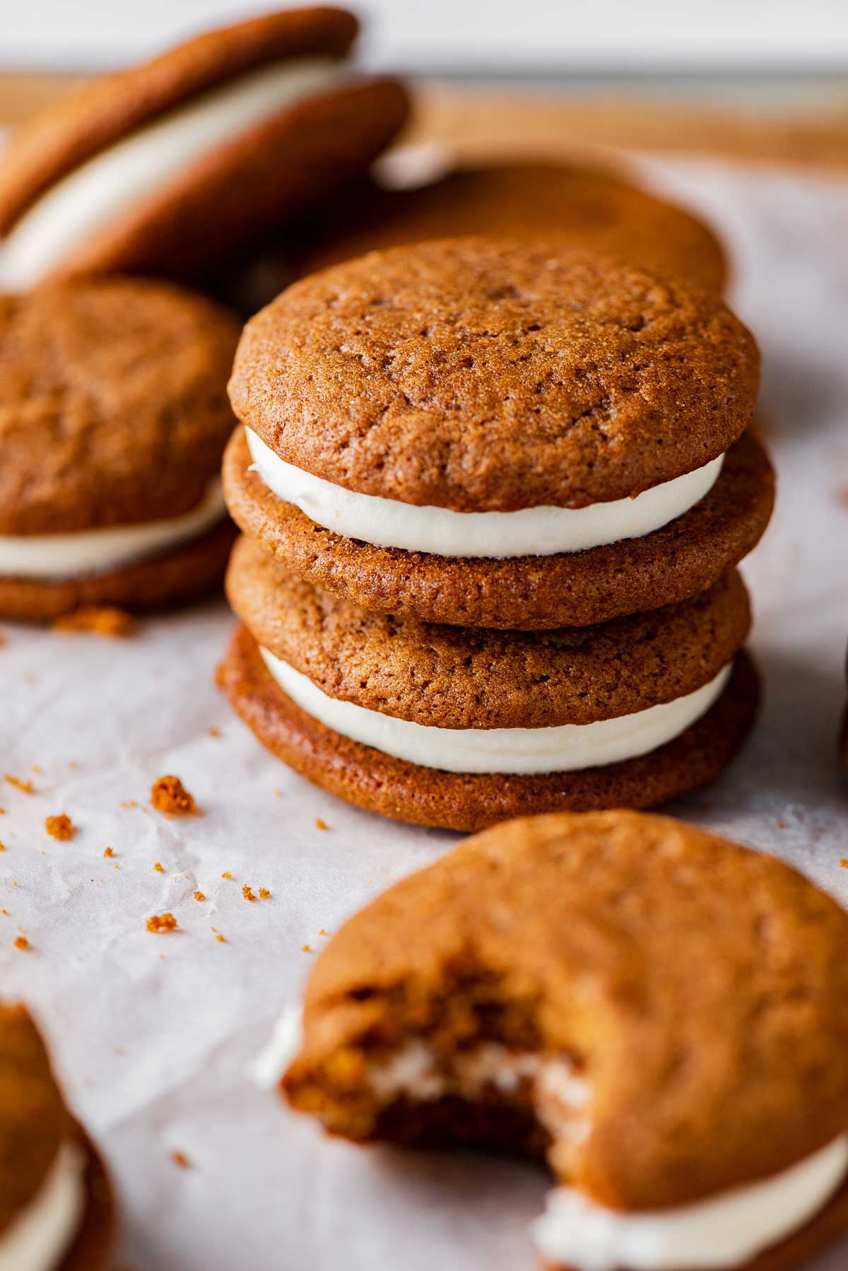 Stacked gingerbread whoopie pies filled with cream cheese frosting on a parchment paper lined baking sheet | © Luyiz®