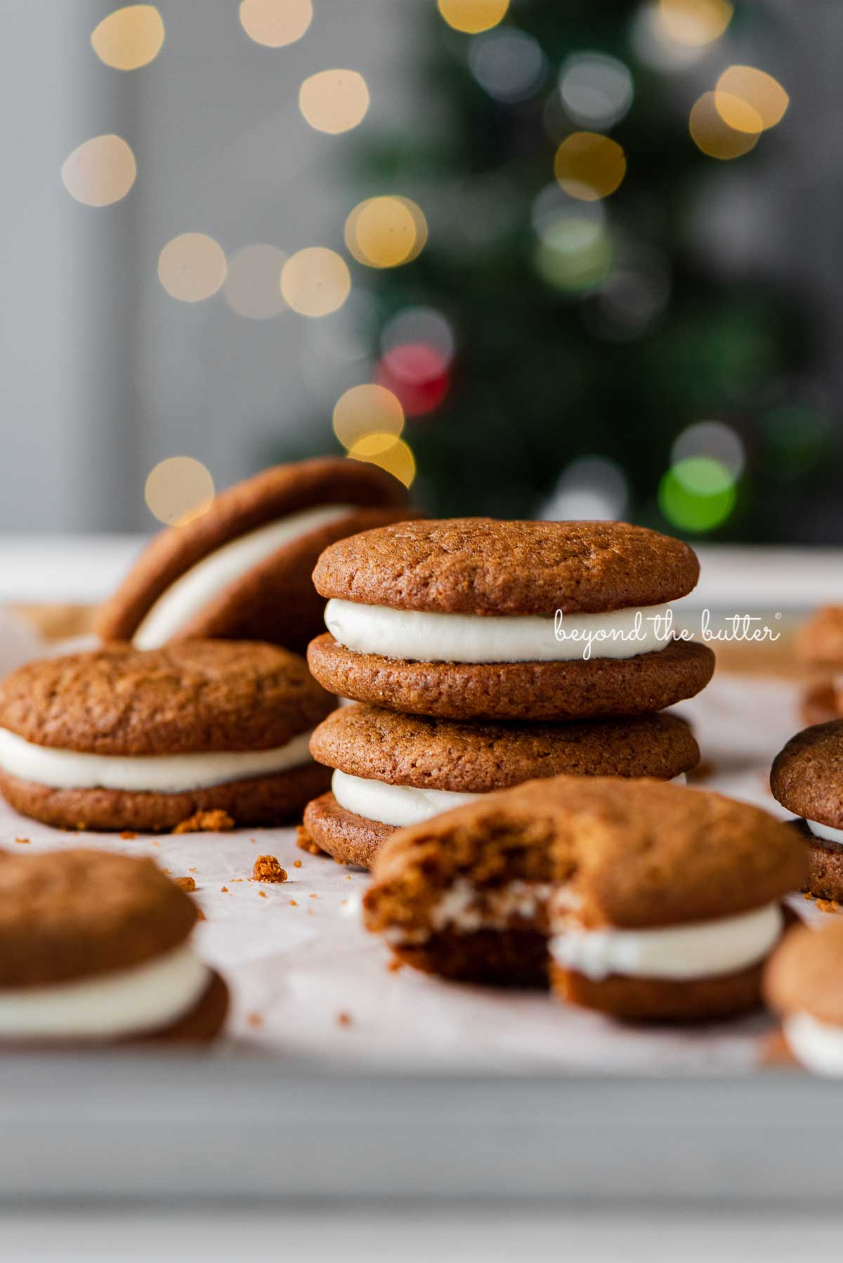 Stacked gingerbread whoopie pies on white parchment paper with holiday tree background | © Luyiz®