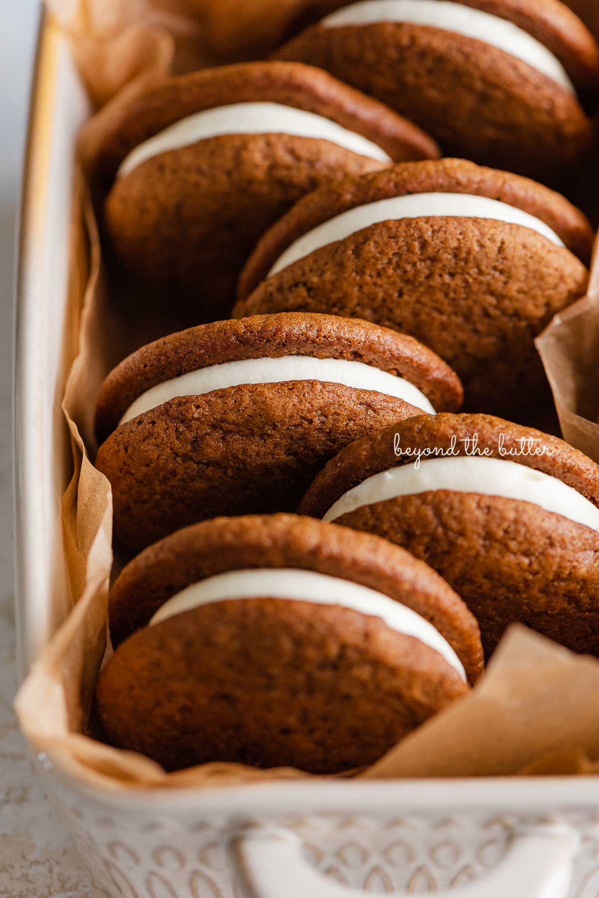 Natural parchment paper lined ceramic baking pan with homemade gingerbread whoopie pies | © Luyiz®