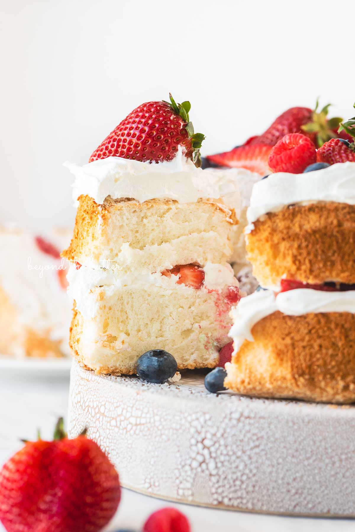 Angel food cake with once slice pulled out with on a ceramic cake stand | © Luyiz®