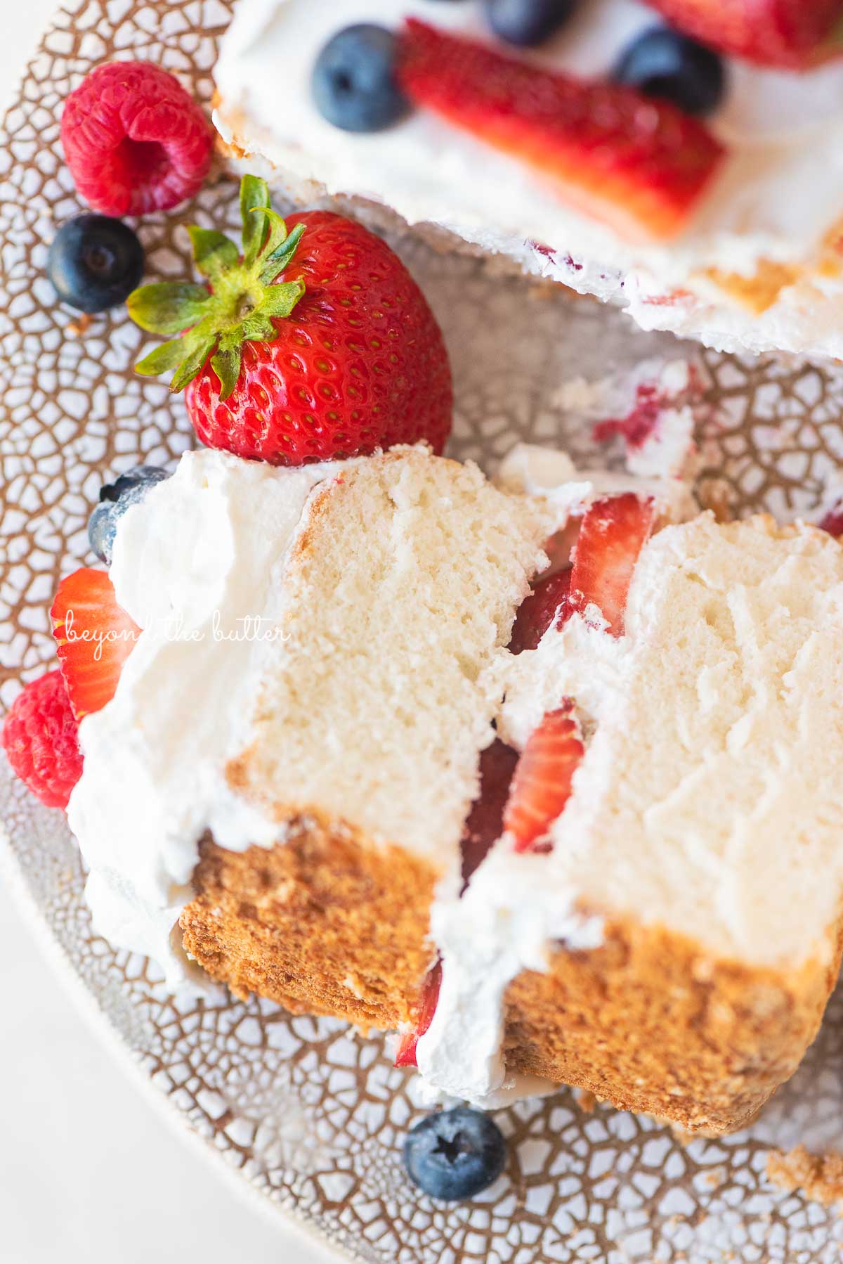 Close up image of angel food cake with one slice on its side on a ceramic cake stand | © Luyiz®