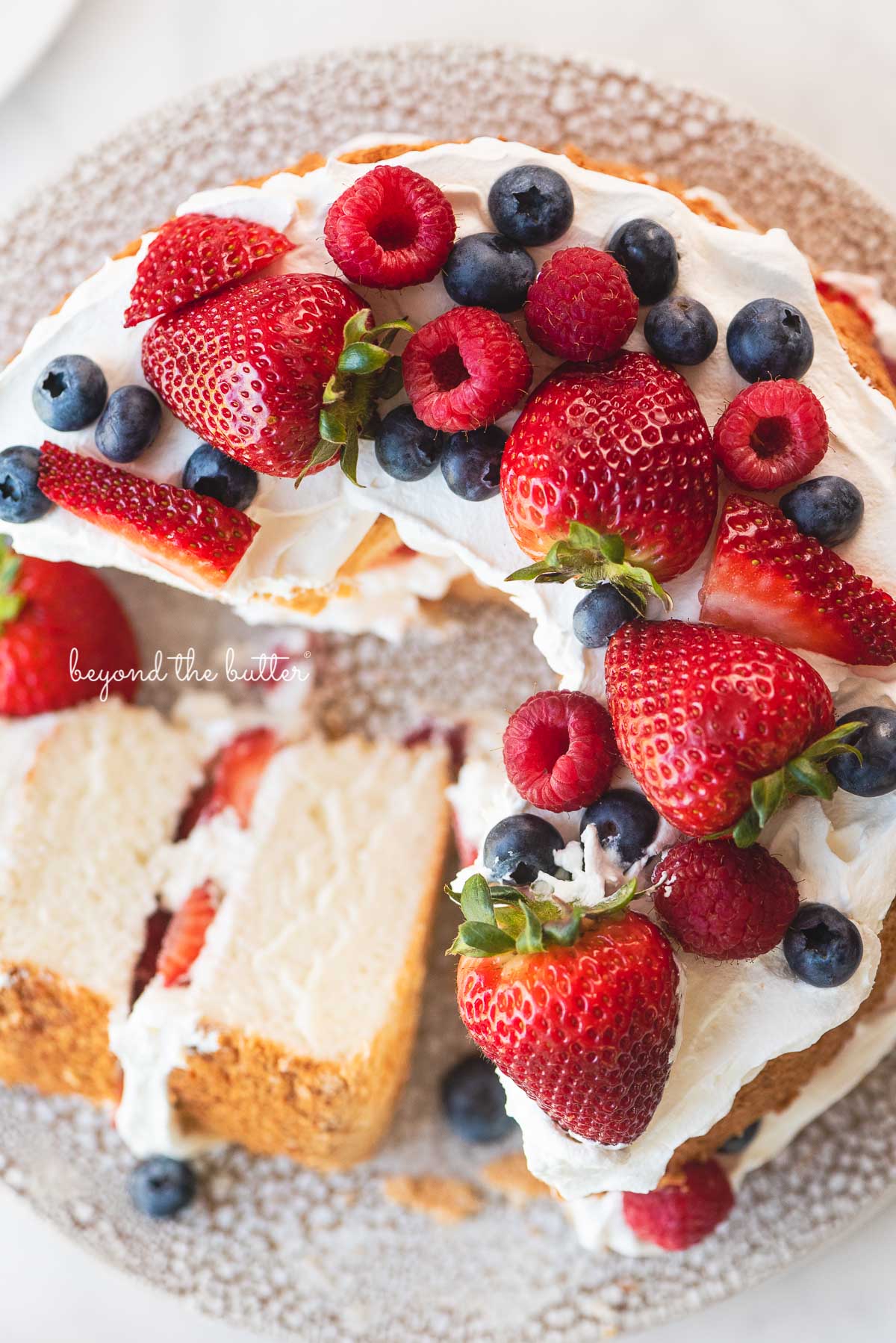 Angel food cake with one slice on its side on a ceramic cake stand | © Luyiz®